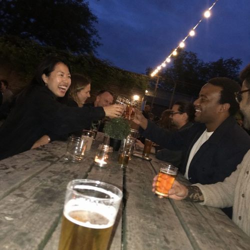 Flash photo of a toast across a pub garden table under fairy lights